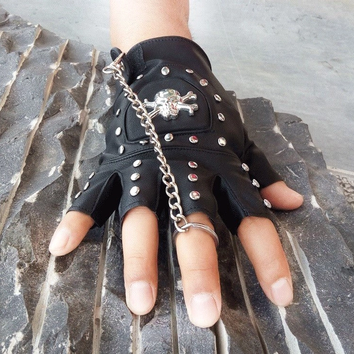 Punk style half-finger gloves in black with metal skull and chain embellishments - fashion photography