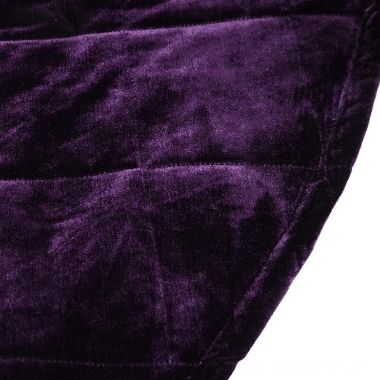 Close-up fabric detail showing shiny deep purple velvet with quilted stitching lines