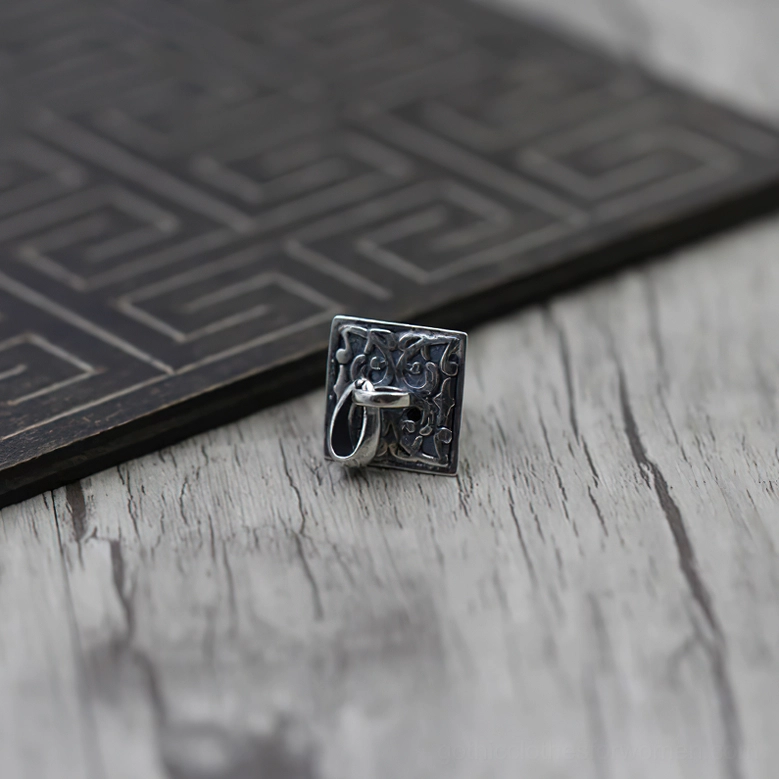 Back of antique pyramid pendant with visible hanging buckle, front top view on light wood table with dark geometric panel showing 925 sterling silver pendant closure