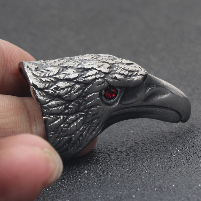 Gothic raven ring on fingertips with red cubic zirconia eye and textured feather details close-up