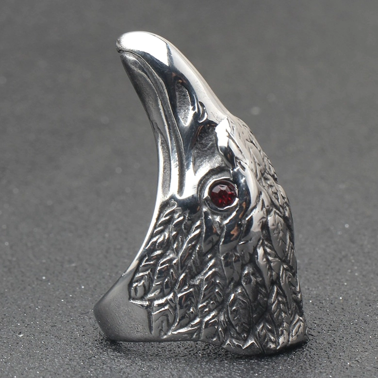 Raven head ring left inner side view showing red gemstone eye and intricate feather texture on dark background