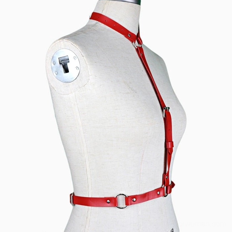 Red synthetic leather body harness with diagonal design on mannequin, left front three-quarter view showcasing strap configuration