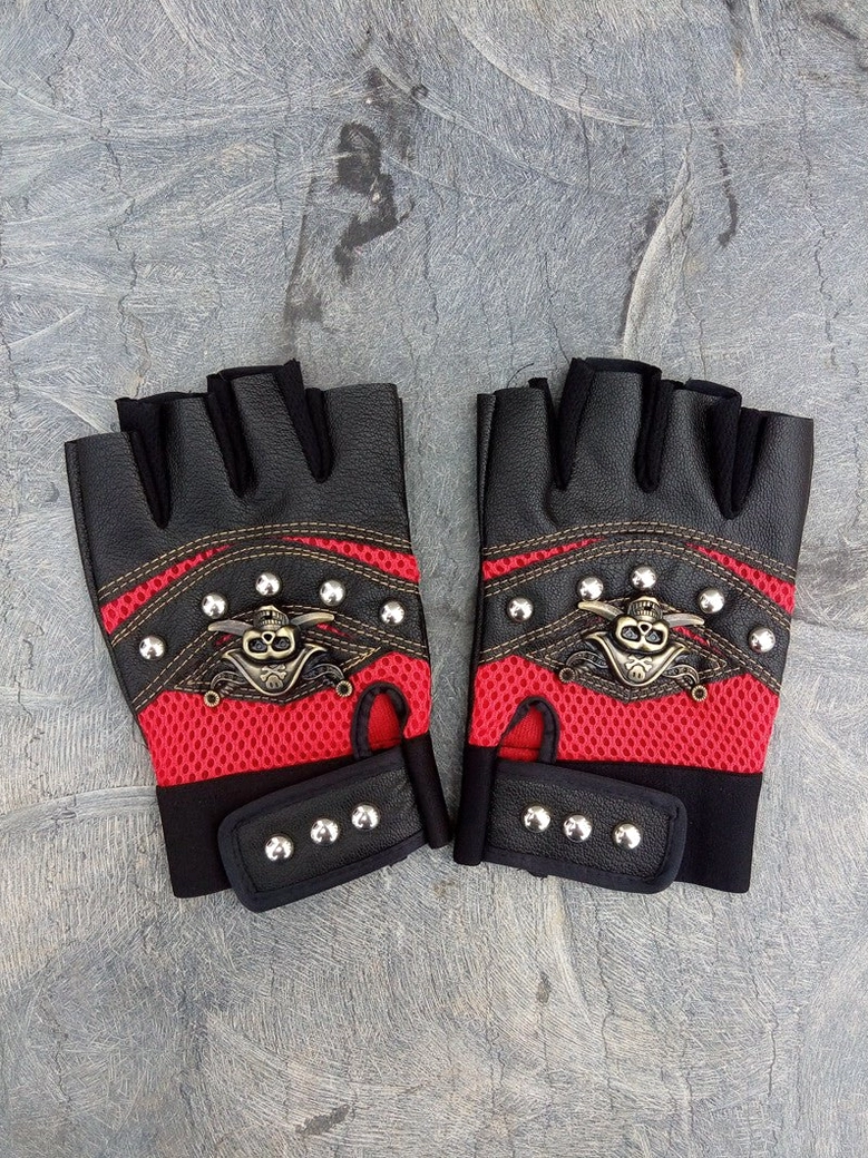 Red mesh half-finger gloves with pirate skull emblem and metal rivets on grey stone surface