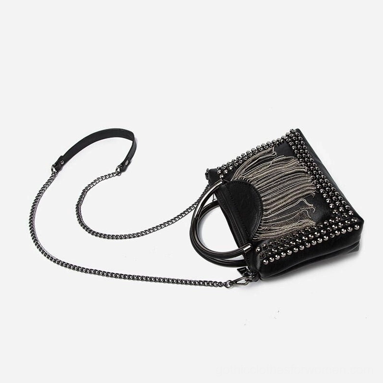 Black studded crossbody bag lying flat showing profile and detachable chain shoulder strap