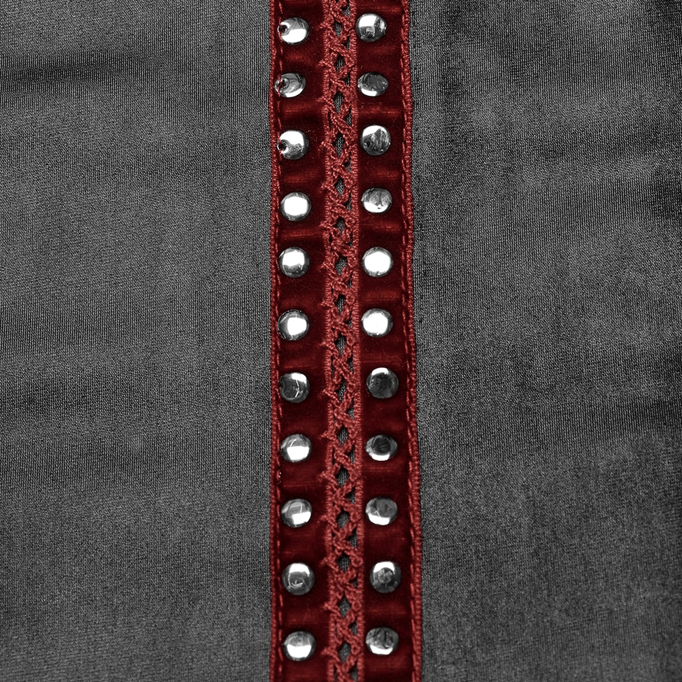 Close-up of red webbing stripe with silver rivets on black faux leather fabric
