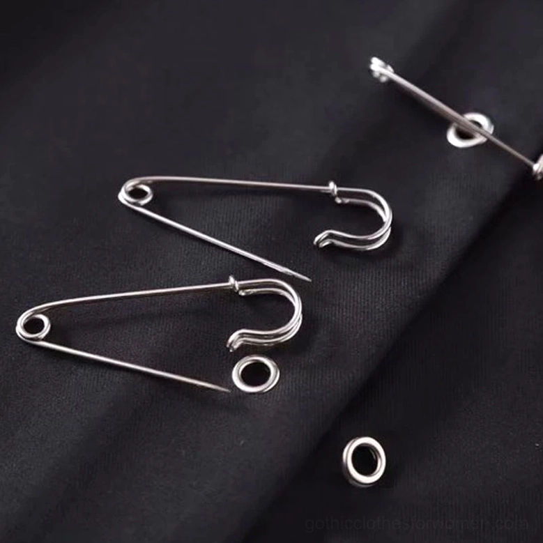Extreme macro detail of silver safety pins and black woven fabric texture with metal grommet accents on gothic mini skirt