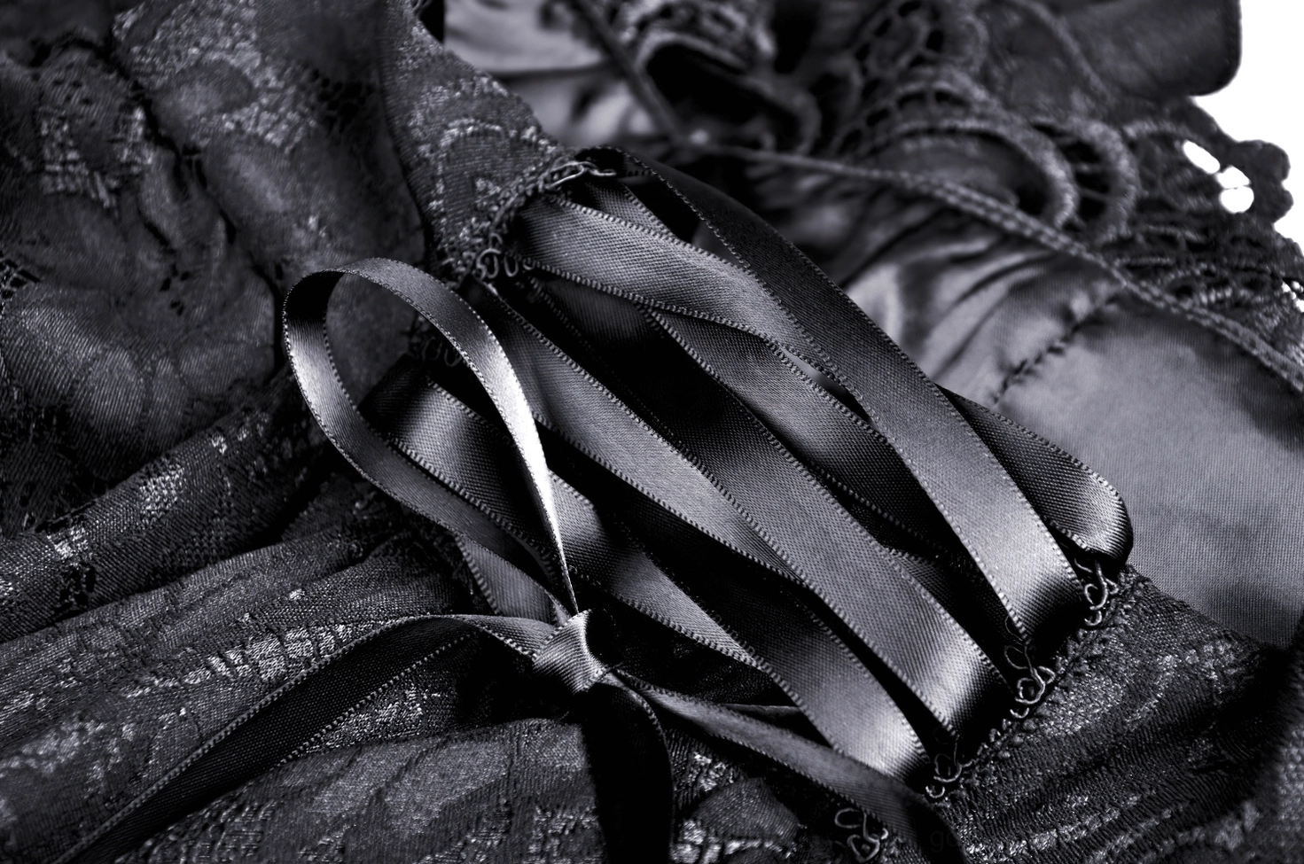 Macro close-up of black satin ribbon bow waist detail with lace base fabric texture