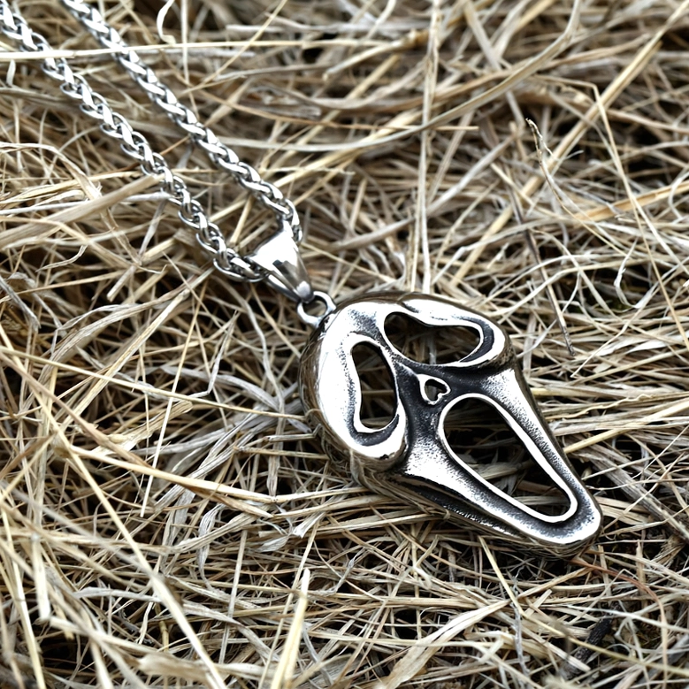 Gothic screaming face pendant necklace overhead view, alternative fashion jewelry on textured outdoor background