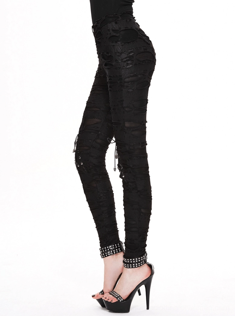 Side full view of black gothic ripped skinny pants with studded ankle straps and distressed fabric details