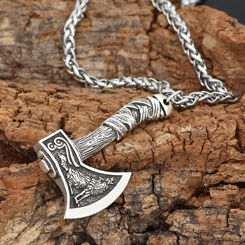 Silver Viking axe pendant with wolf pattern on wheat-link metal chain with dark wood backdrop