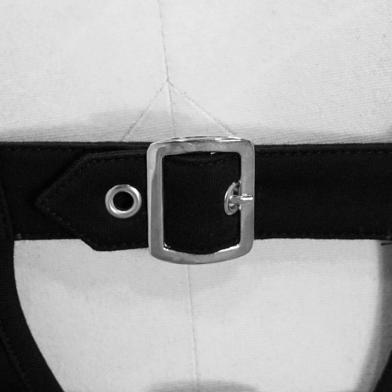Extreme close-up of silver square metal buckle and black leather attachment on punk crop top