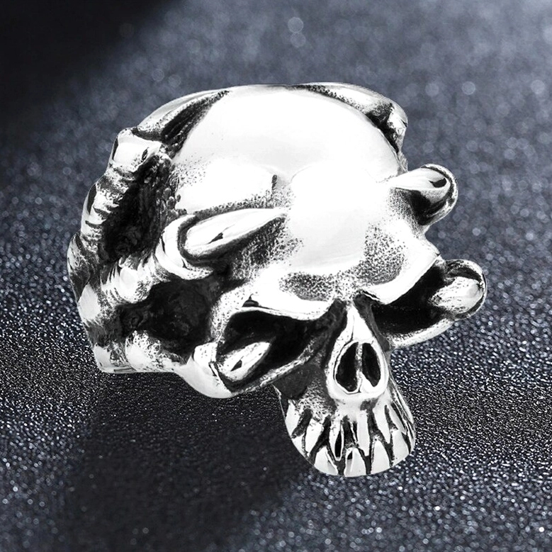 Silver skull claw statement ring - polished stainless steel gothic skeleton jewelry, flat front view on textured background