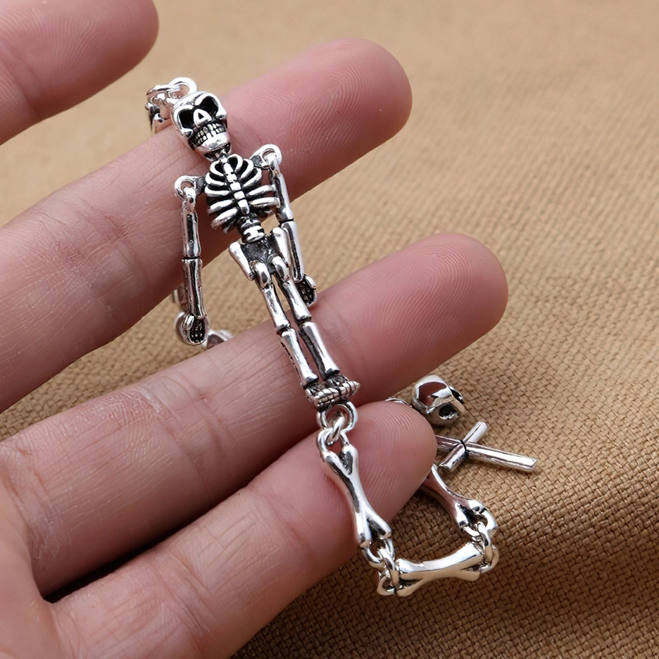 Close-up side view of skeleton gothic bracelet worn on human wrist, showing distressed oxidized silver finish and detailed skeleton pendant charm