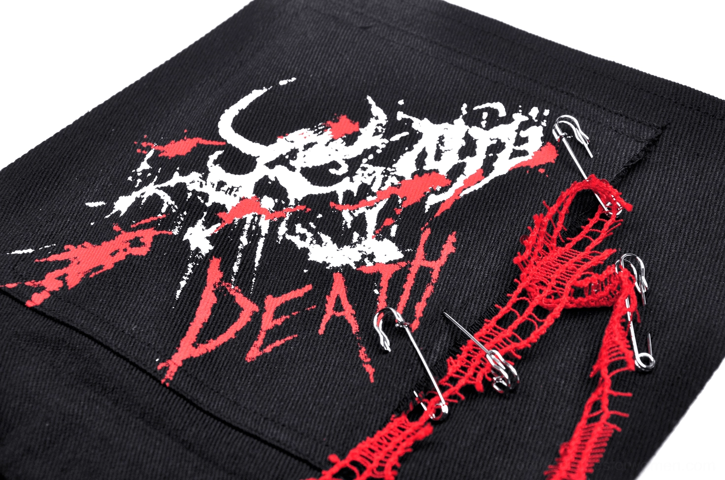 Embroidery detail of skull motif with death lettering, red tassels, and safety pin accents on dress