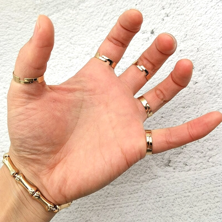 Polished gold skeleton hand bracelet with minimalist finger rings design close-up detail