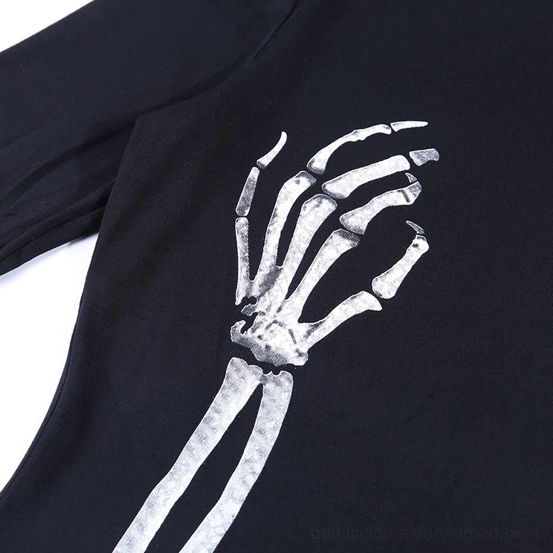 Flat lay close-up of white skeleton hand and arm graphic print on black fabric, showing print clarity and design detail