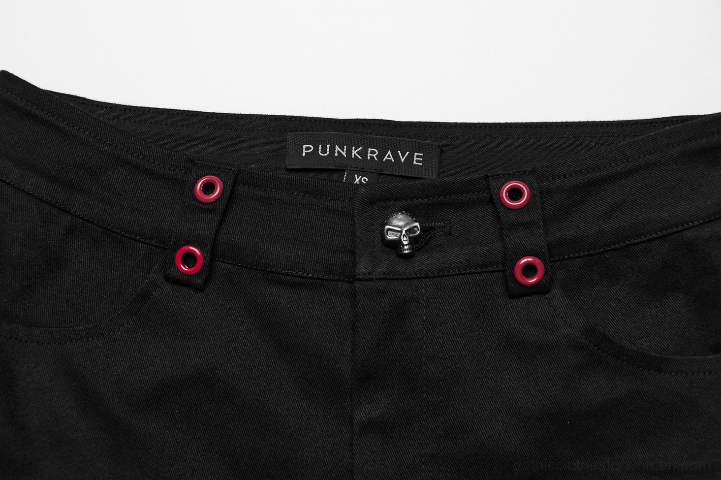 Close up waistband skull button and red eyelets on black gothic flared pants