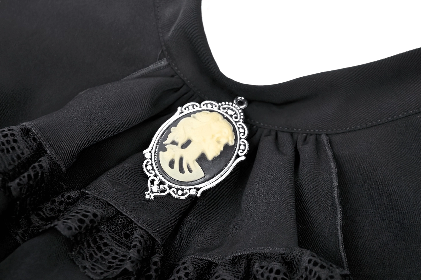 Extreme close-up of sterling-silver-toned ornate skull cameo with ruffled black lace trim on gothic dress brooch