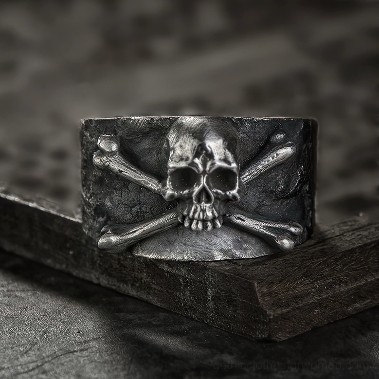 Stainless steel skull crossbones gothic ring displayed on vintage wooden base showing flat stable placement