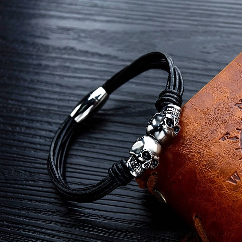 Dual skull rope cord bracelet side angle photography next to leather notebook styling shot
