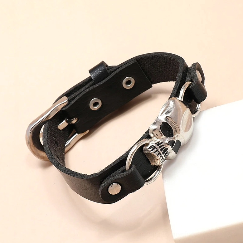 Low angle view of antique silver skull leather cuff bracelet showing adjustable strap design