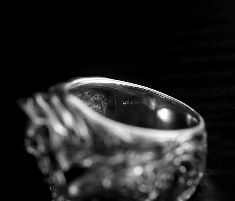Inner band of sterling silver skull ring showing polished interior and engraved exterior texture on dark background