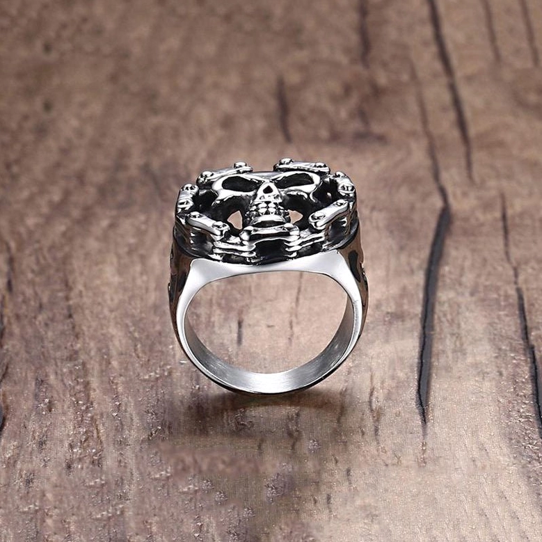 Rear three-quarter view of stainless steel skull signet ring highlighting geometric cross cutout band design on wooden background