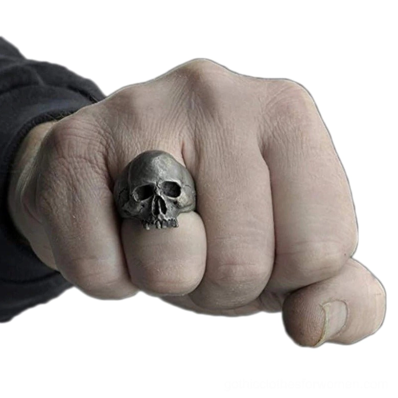 Gothic skull ring worn on male hand middle finger, frontal view against white background