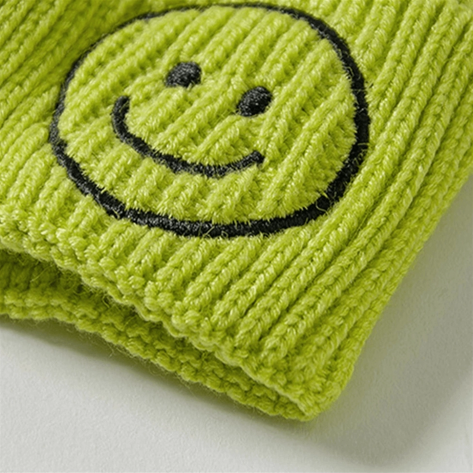Smiley face embroidered knit beanie detail shot showing ribbed texture and embroidery quality, dark aesthetic hat