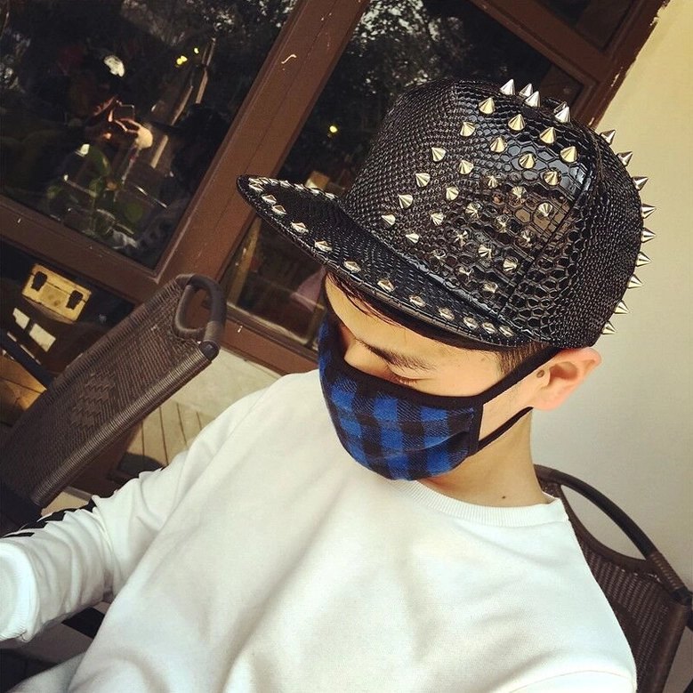 Male model wearing snakeskin gothic cap with studs and spikes, side angle styling shot in casual setting with blue plaid mask, unisex punk cap