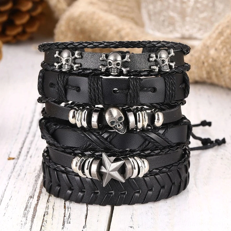 Stacked black leather gothic bracelets showing skull and star designs with braided leather and metal hardware accents on wooden table