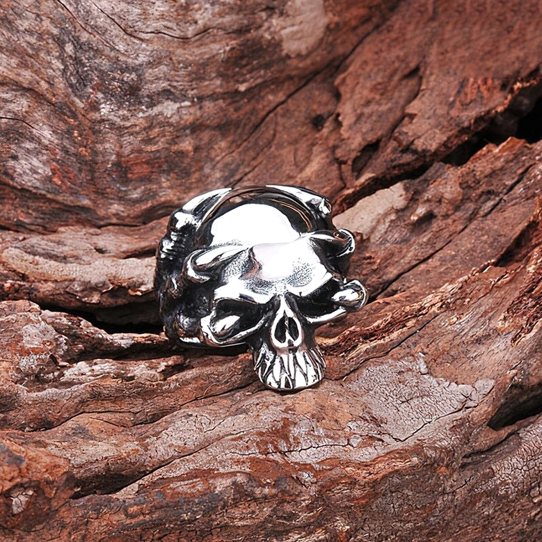 Stainless steel skull claw ring - detailed gothic skeleton design, overhead front view on wood background