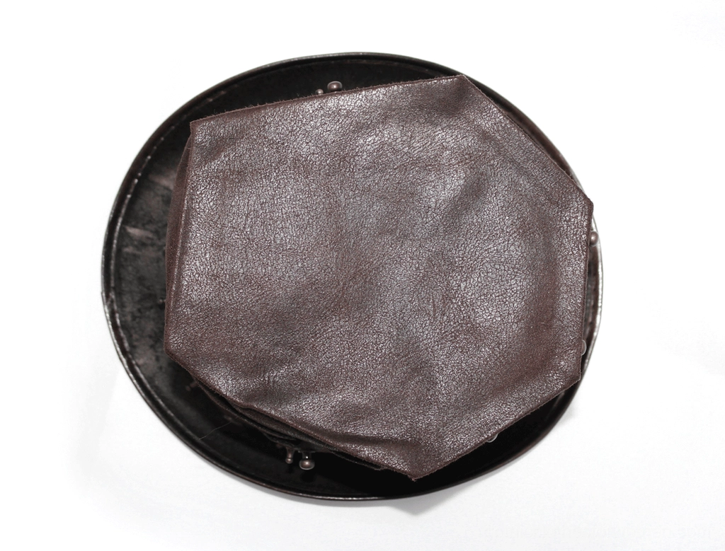 Brown PU leather steampunk top hat with skull metal ornament displayed on flat surface, showcasing hexagonal crown and rivet details
