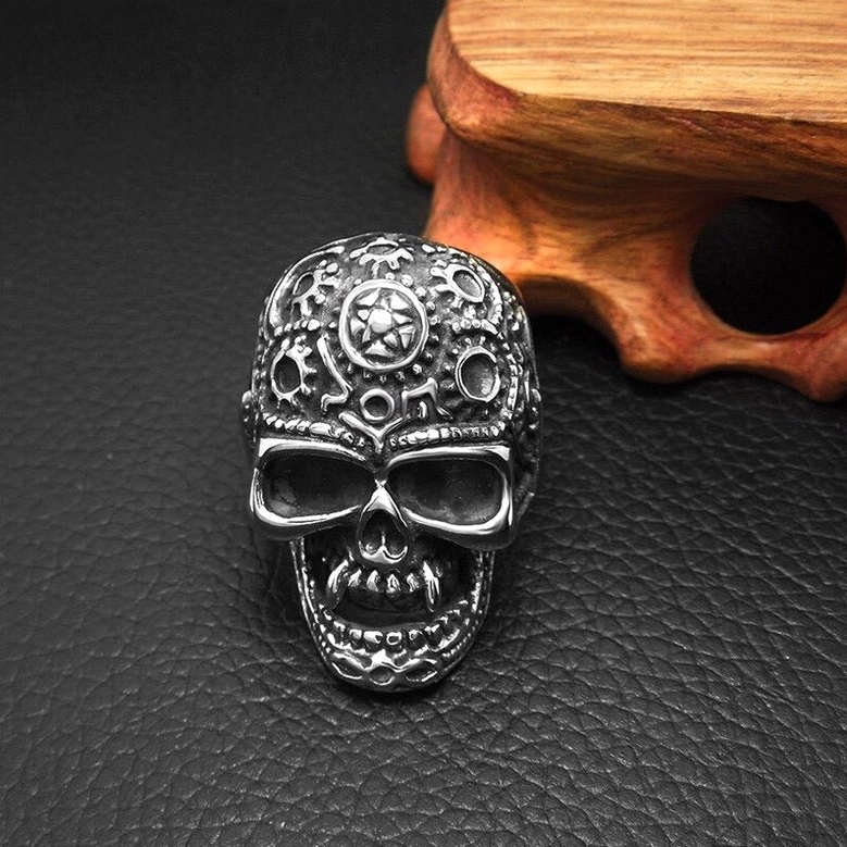 Steampunk gothic ring on leather display mat and wooden stand, front view showcasing full gear engraved skull design