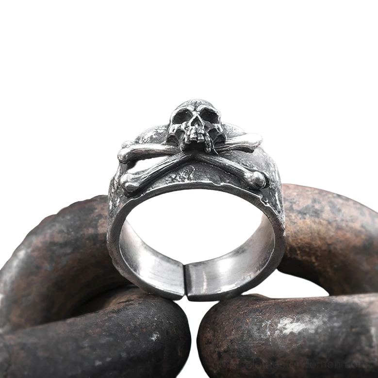 Overhead view of gothic ring on dark metal chains background, showcasing polished inner band and weathered silver texture