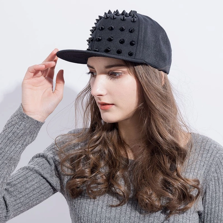 Model in left profile wearing black spiked cap, demonstrating adjustable fit and styling