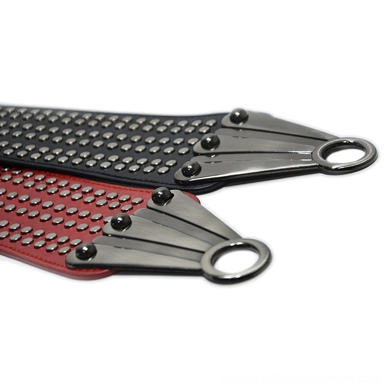 Close-up macro detail of black and red studded gothic belt showing dense metal rivets and silver fan-shaped fasteners