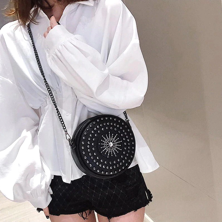 Female model wearing black studded shoulder bag on hip with white shirt styling