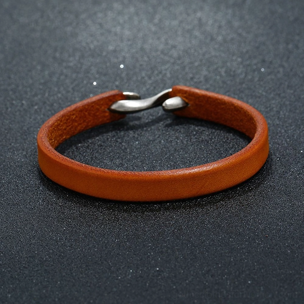 Tan genuine leather narrow cuff bangle with dual silver hook clasp - flat lay dark background