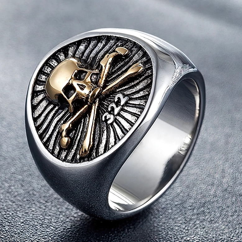Gold and silver skull pirate ring with 322 engraving on dark leather background, top view
