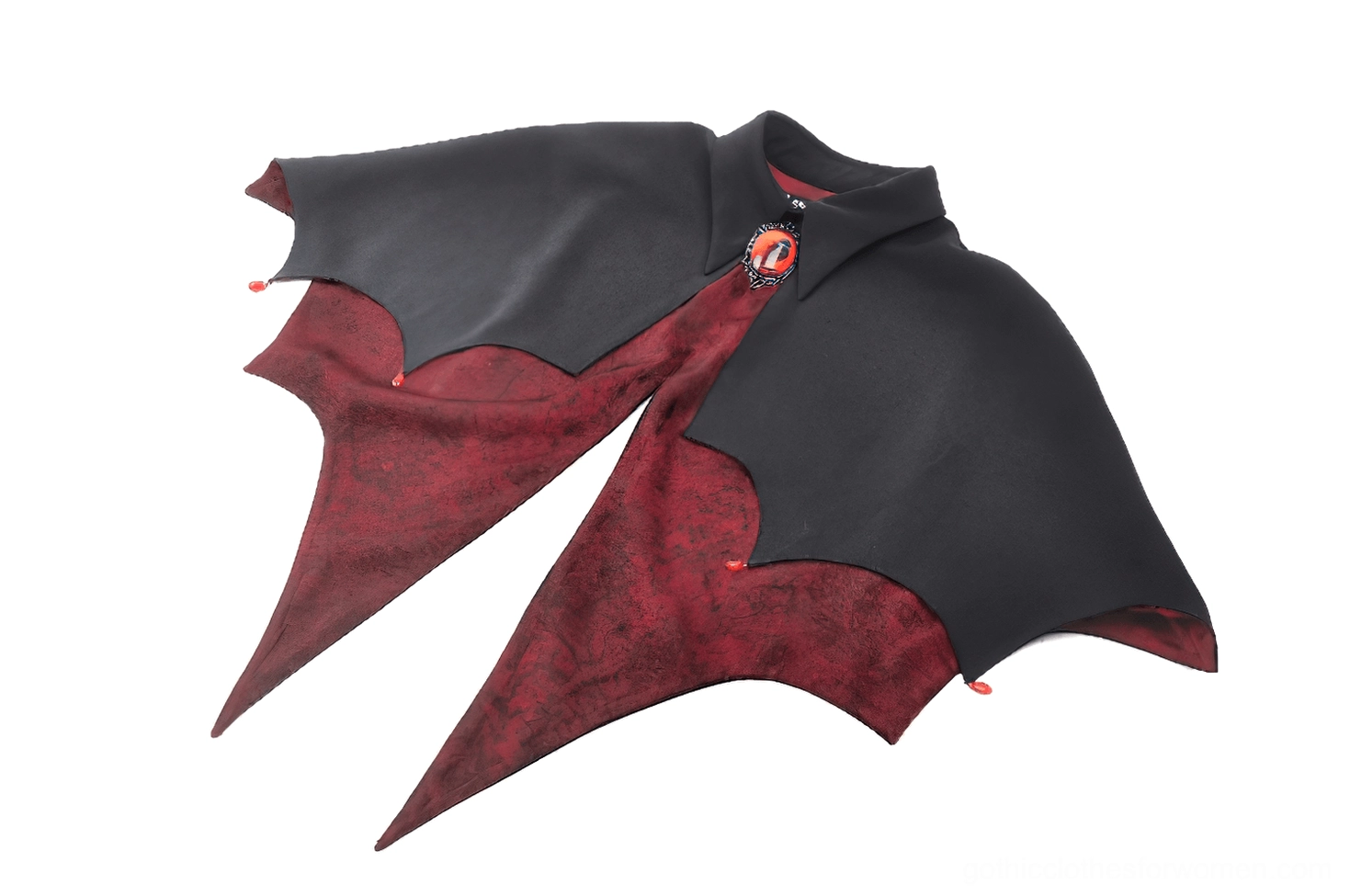 Angled side view of vampire cape displaying reversible two-tone construction with black exterior, bright red inner lining, and jeweled brooch clasp