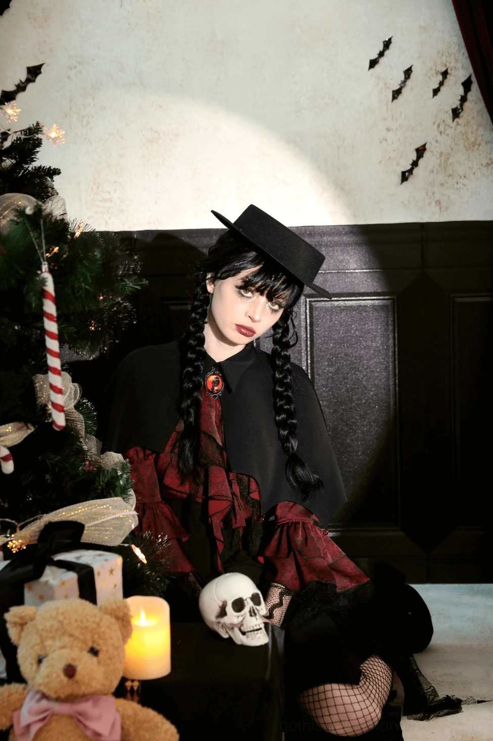 Studio photograph of black vampire cape displaying full silhouette, pointed bat-wing hem structure, and jeweled brooch clasp from front angle