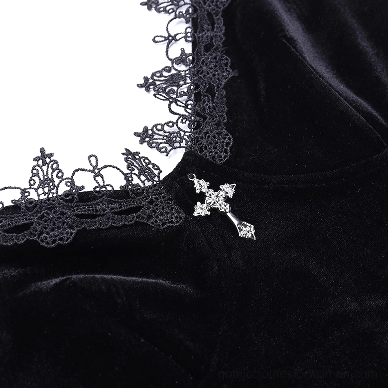 Close-up of embroidered lace trim and crystal cross pendant on black velvet dress