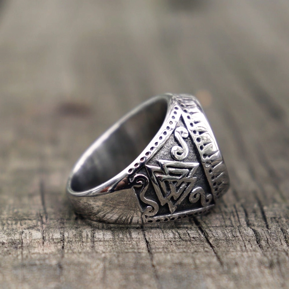 Viking knotwork ring left three-quarter on wooden tabletop polished silver band engraved knot patterns