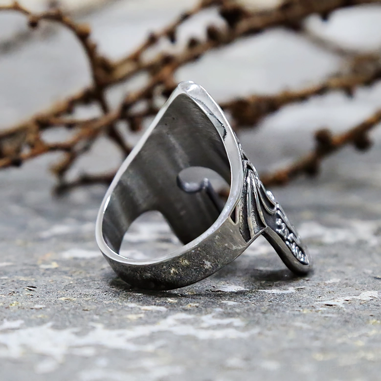 Viking helmet ring back view inner band engraved tribal patterns stone background