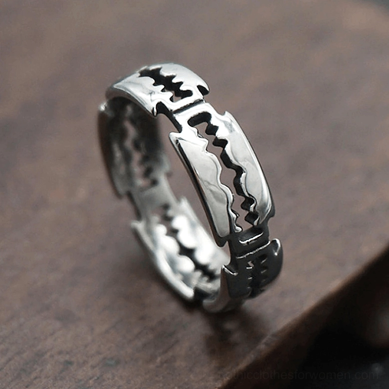Vintage-style punk blade ring with aged darkened finish, razor blade shape design, oblique side close-up on wooden surface