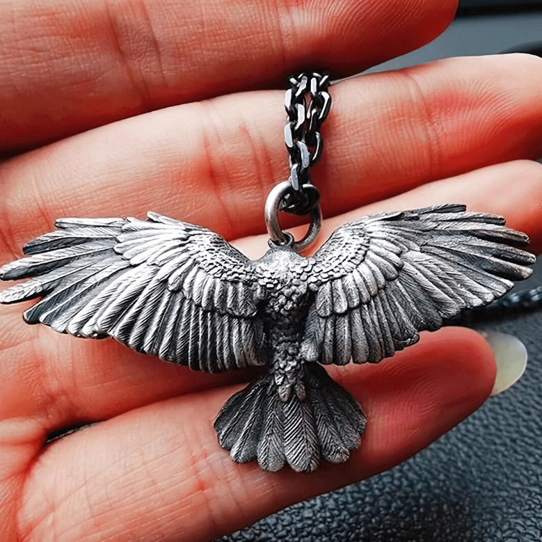 Rear view of blackened silver crow pendant necklace on fingers showcasing detailed back feather carving and craftsmanship