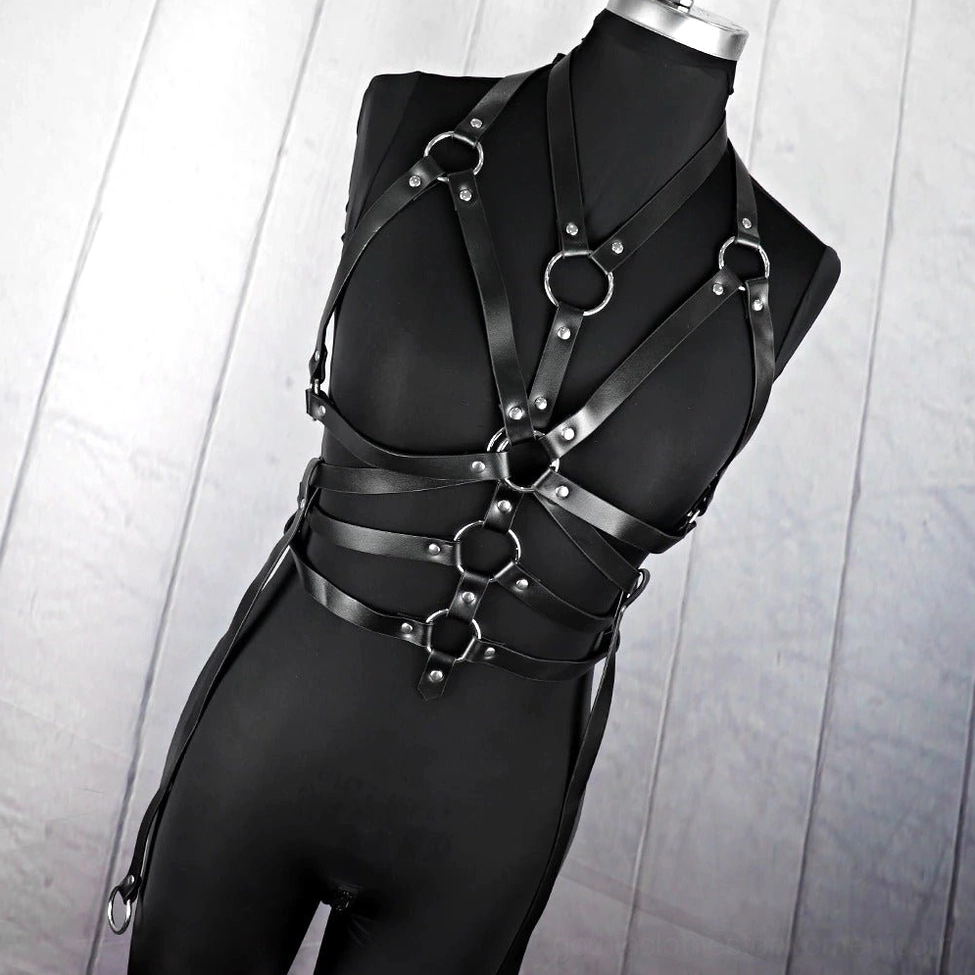 Low angle front view of waist-to-chest bondage harness featuring black faux leather and multiple circular metal buckles