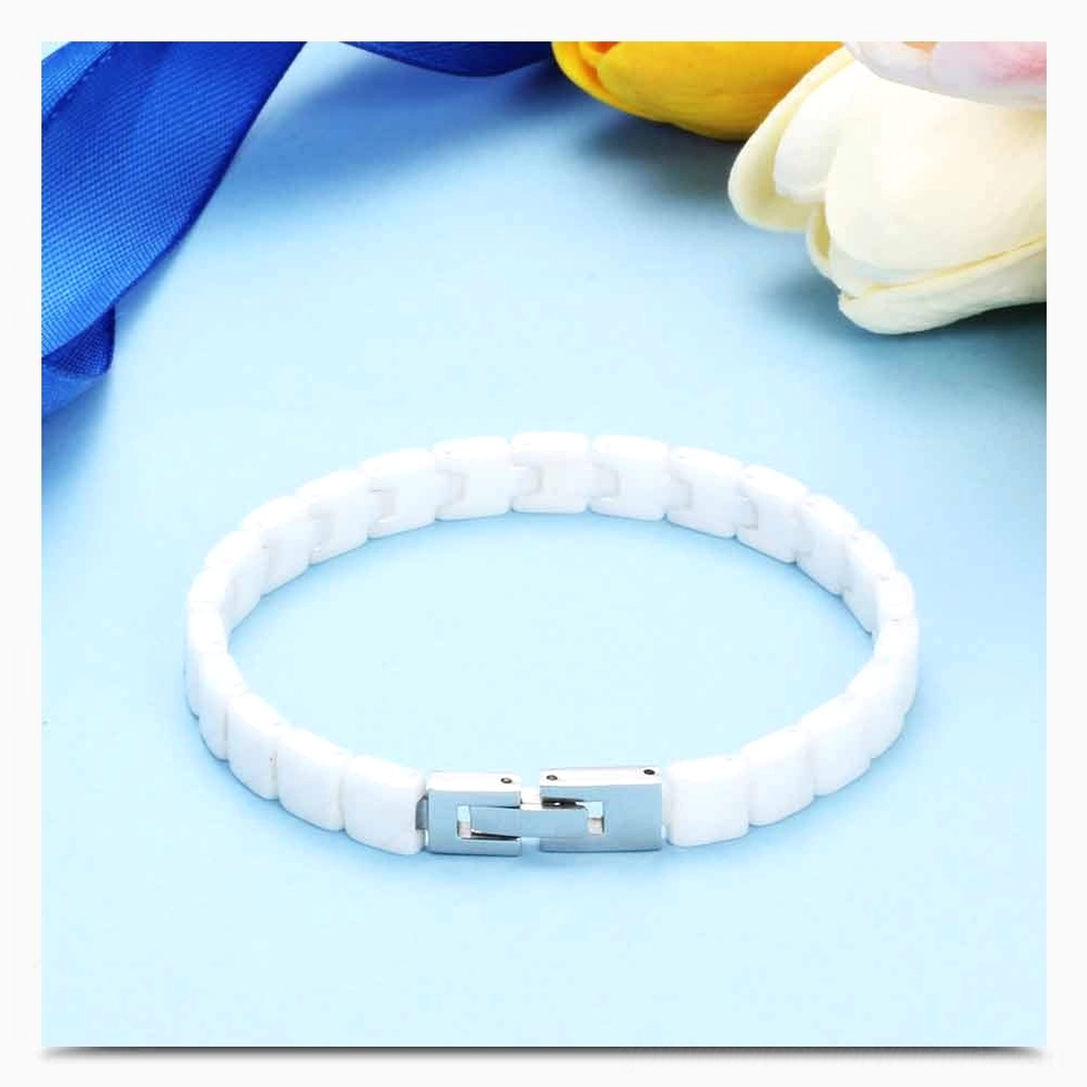 White ceramic bracelet styled with floral tulip background and blue backdrop aesthetic