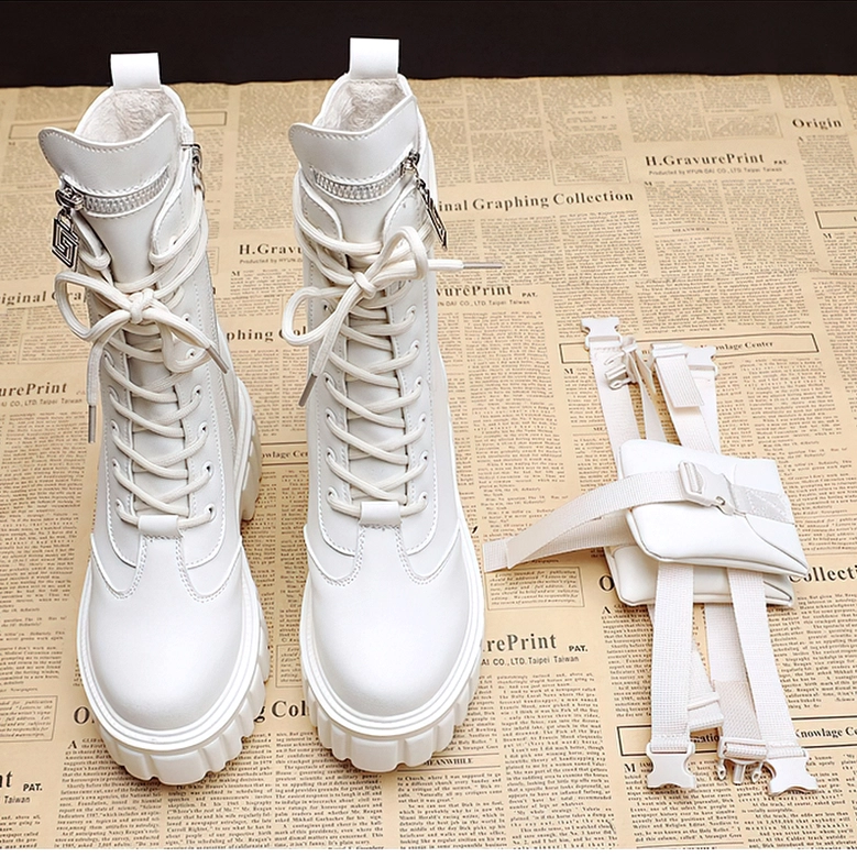 Pair of white platform lace-up combat boots displayed flat with matching decorative straps on newspaper background